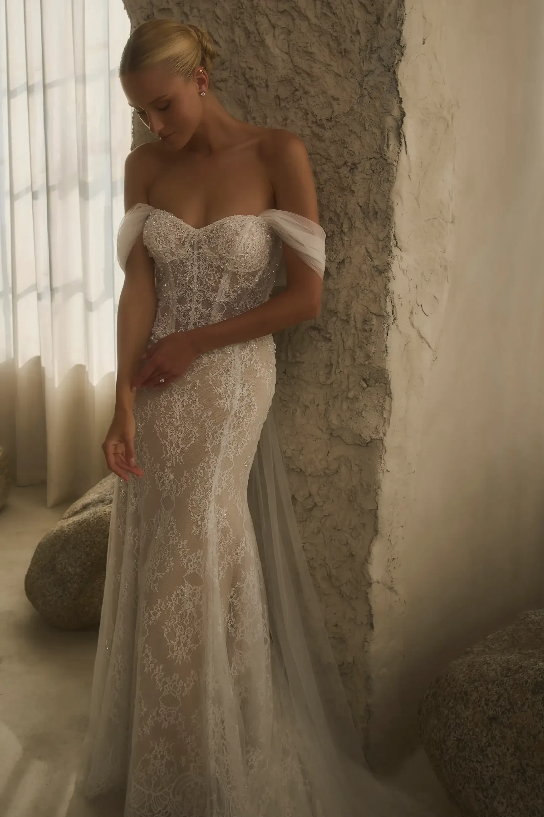 model is wearing a lace off the shoulder wedding dress
