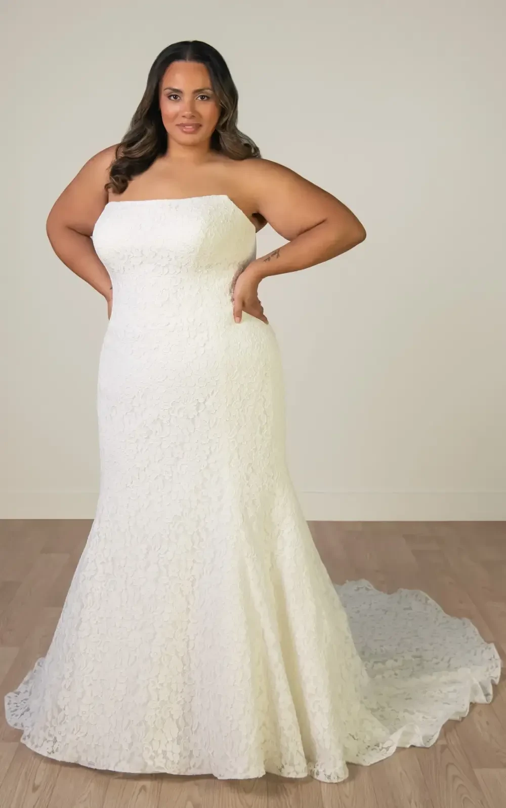 model is wearing a strapless lace fit and flare plus size wedding dress