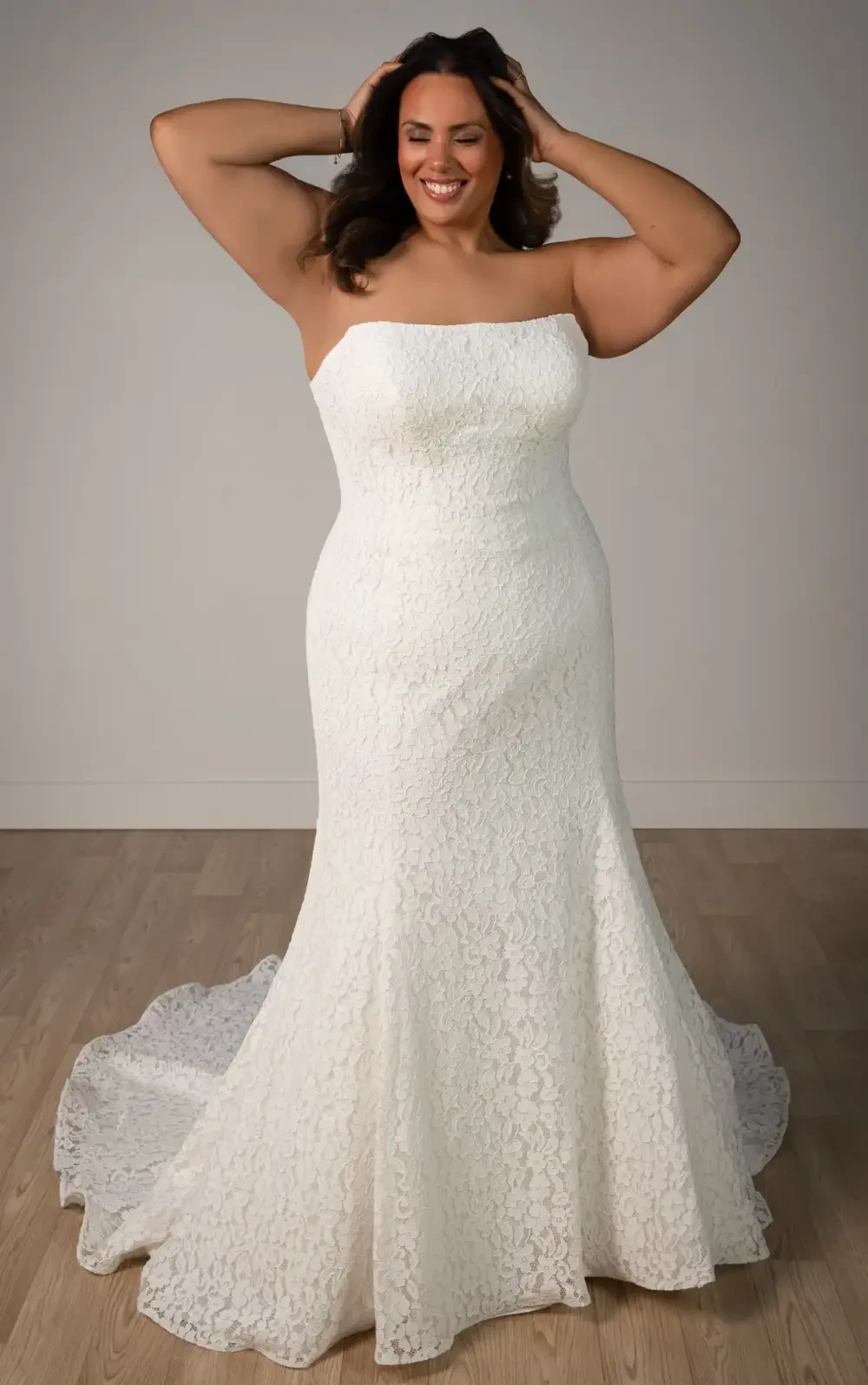 model is wearing a strapless lace fit and flare plus size wedding dress
